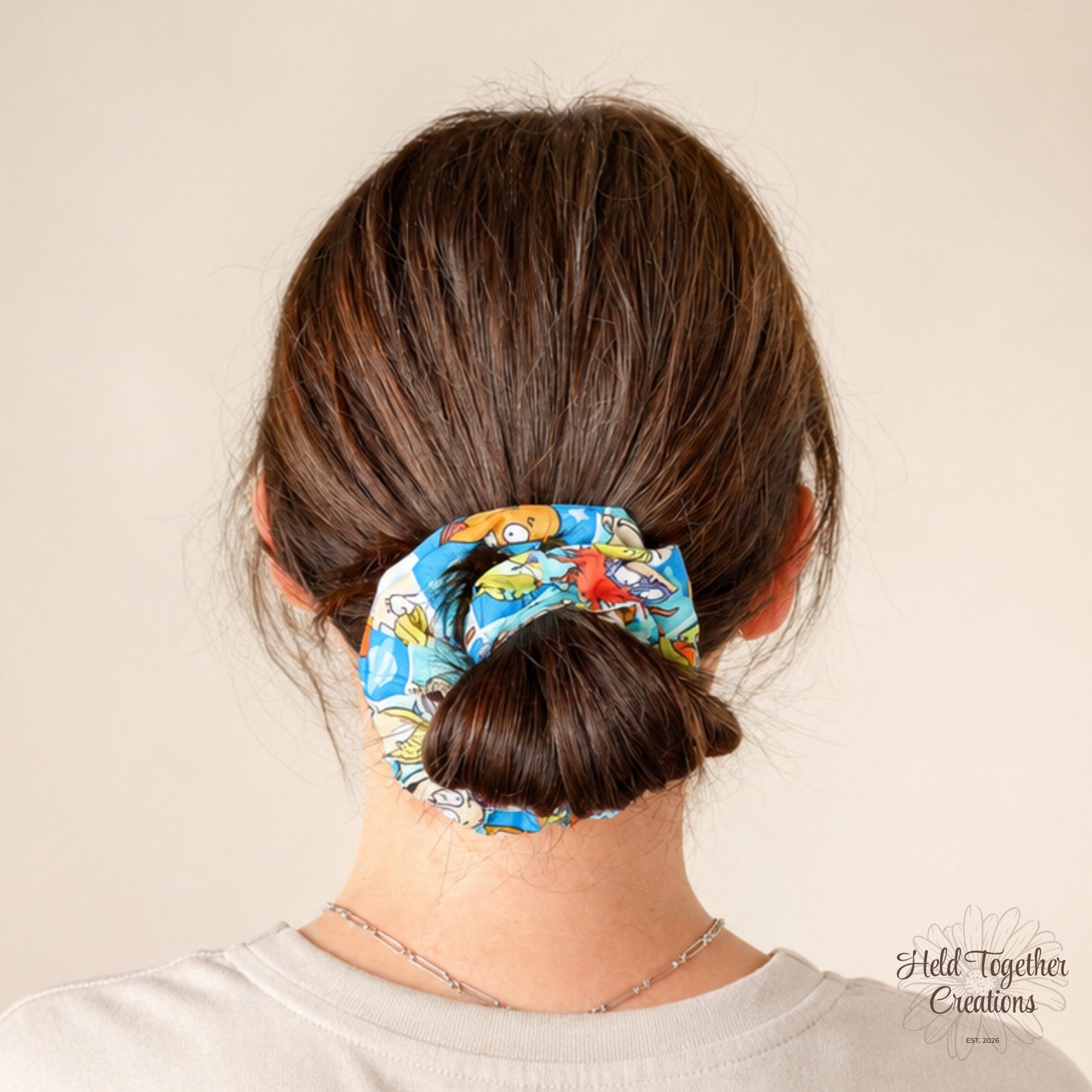 Colourful 90s Chaos handmade scrunchie with bright retro cartoon-style print on a warm ivory background.