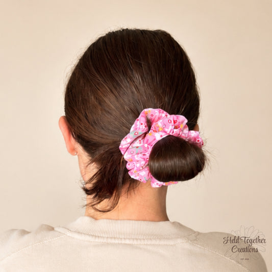 Person with a floral scrunchie in their hair against a beige background