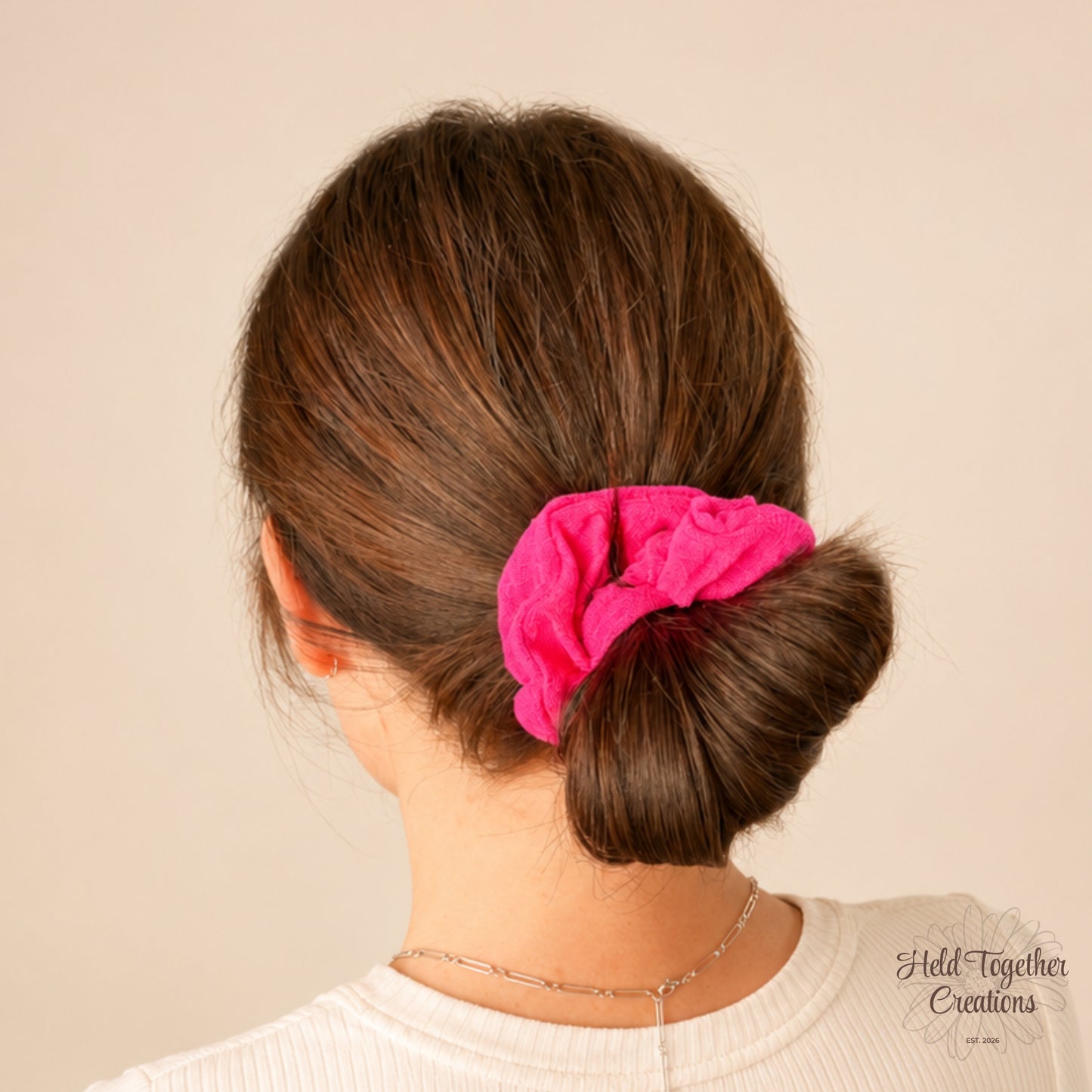 Berry pink linen-look scrunchie styled in a low bun on warm neutral background.