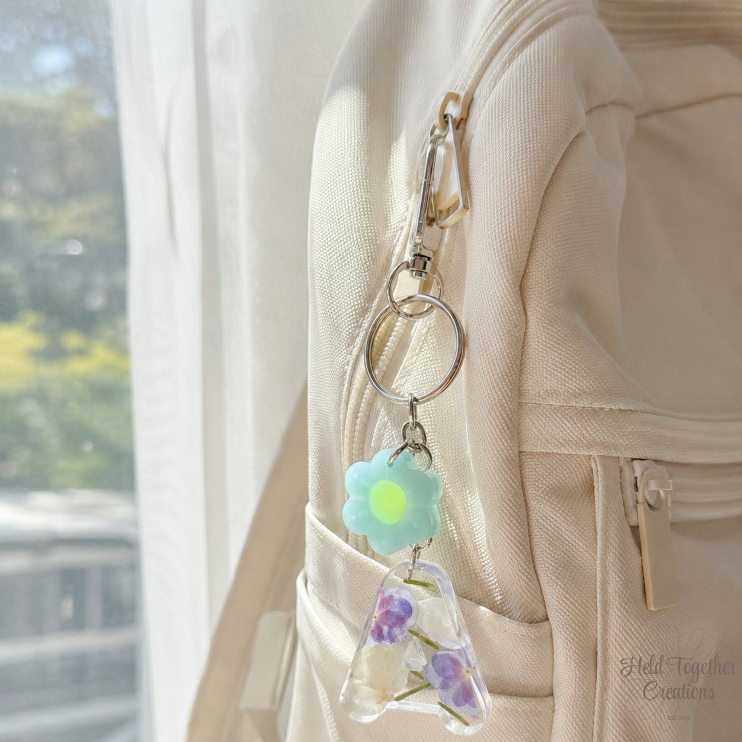 Handmade clear resin initial keyring with blue and purple floral details and a daisy charm on silver hardware.