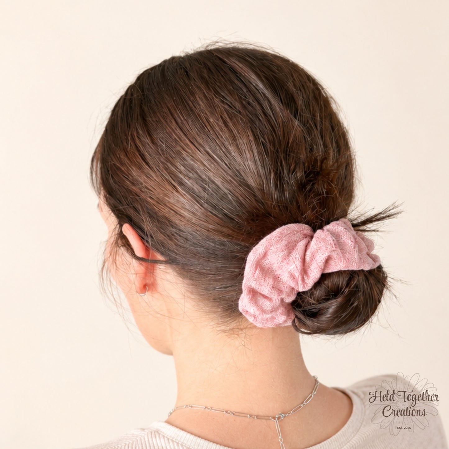 Blush pink textured linen-style handmade scrunchie on a warm ivory background.