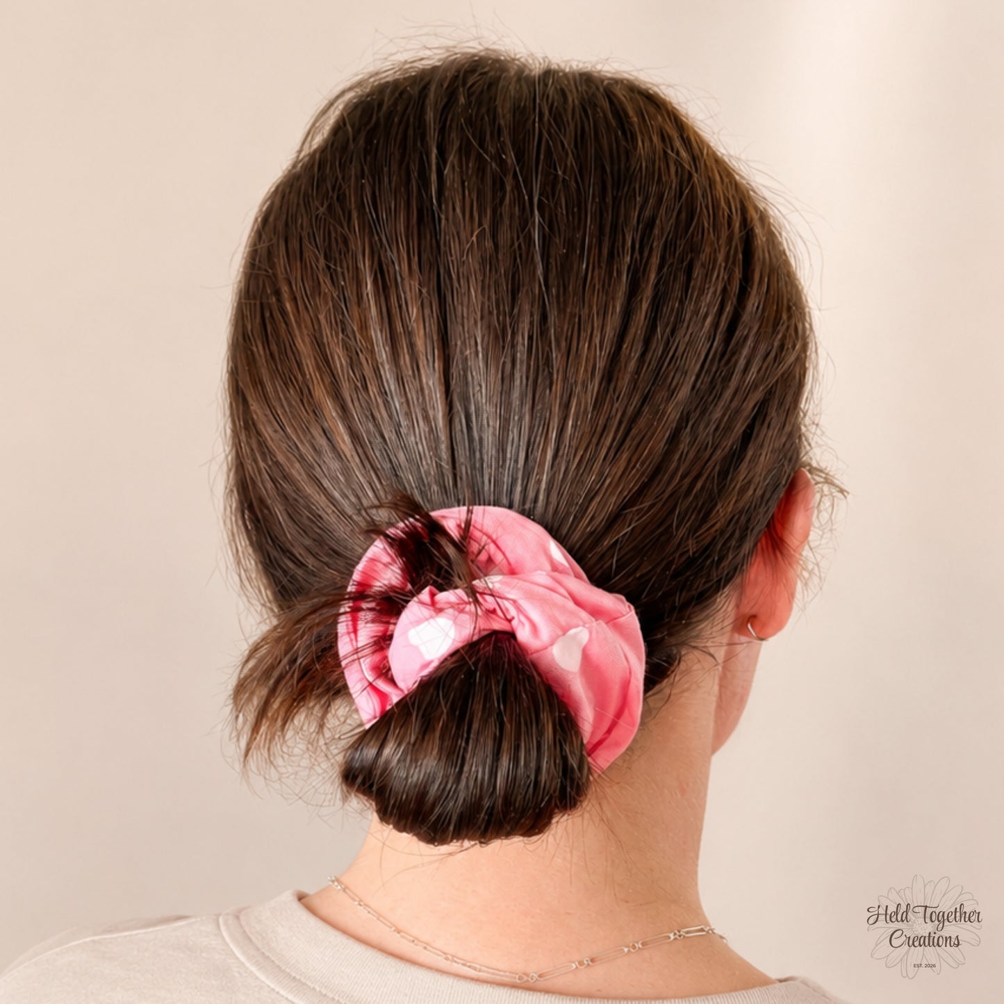 Candy Hearts Scrunchie styled in a low bun, showing the pink heart print fabric in use.