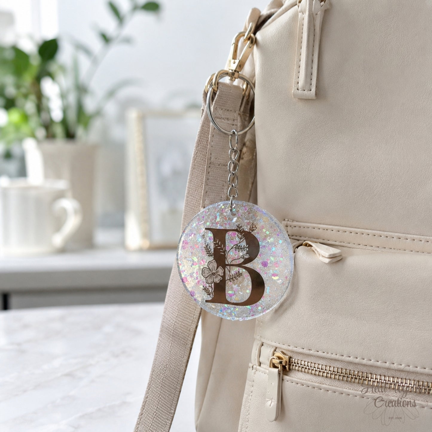 Handmade clear glitter resin initial bag tag with black floral letter B and silver keyring.