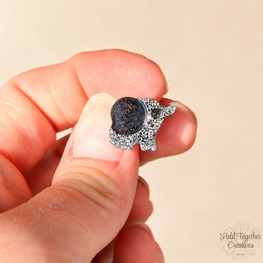 Handmade black and silver speckled elephant resin stud earrings on a soft neutral background.