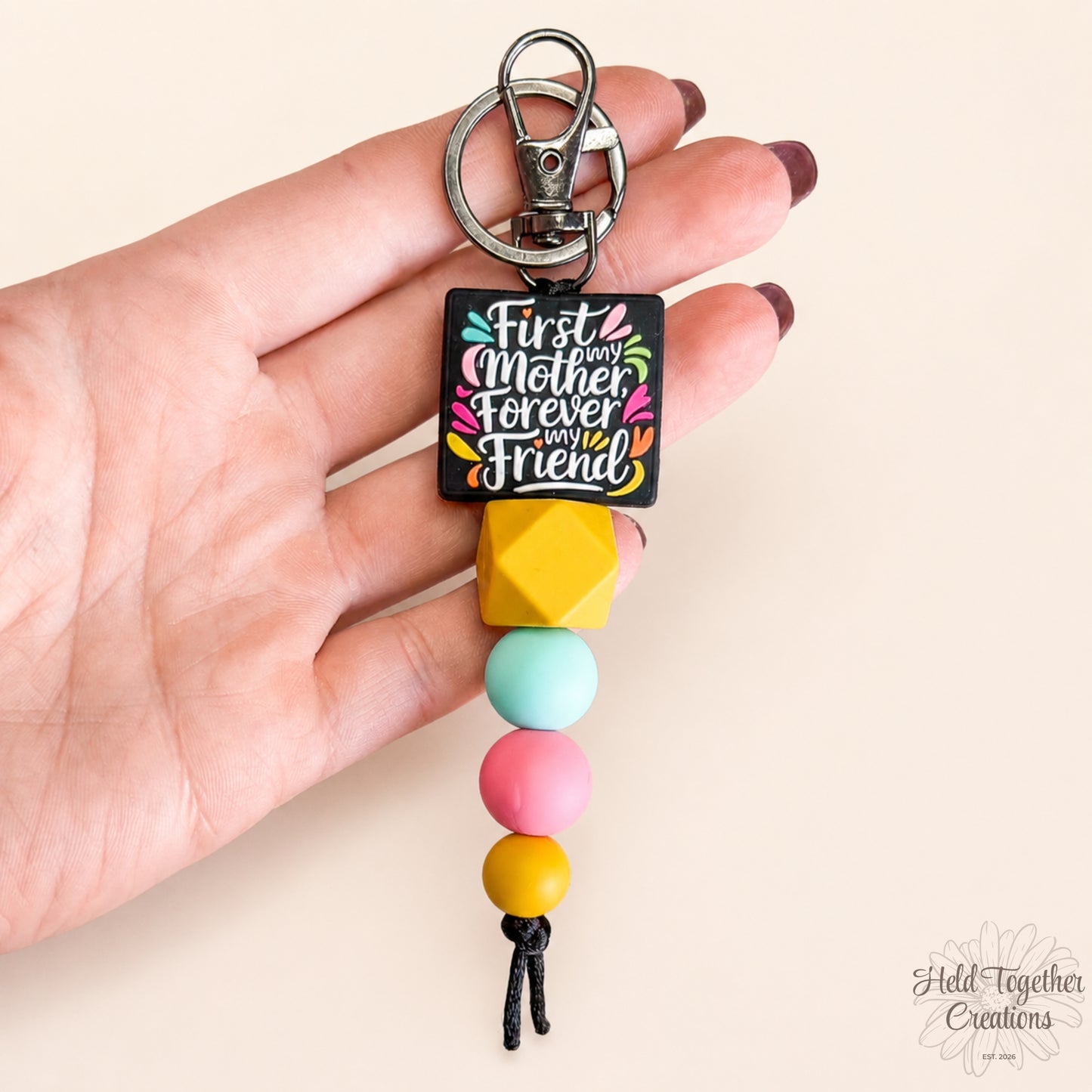 Colorful keychain with text 'First my Mother, Forever my Friend' held by a hand.