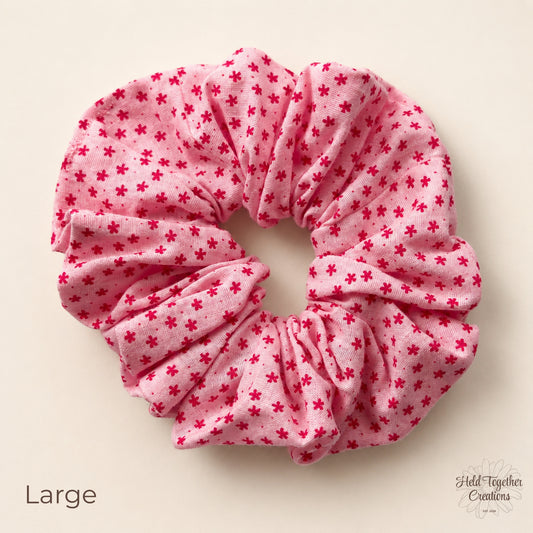 Large Petal Sprinkle Scrunchie laid flat on a warm ivory background showing pink fabric with deep pink mini floral print.