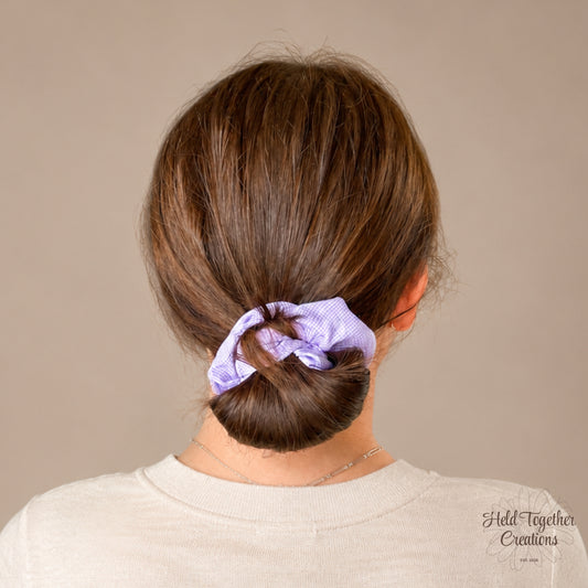 Lilac and white check handmade fabric scrunchie on a soft ivory background.