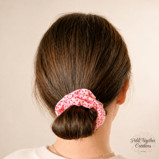 Person with a pink scrunchie in their hair against a beige background
