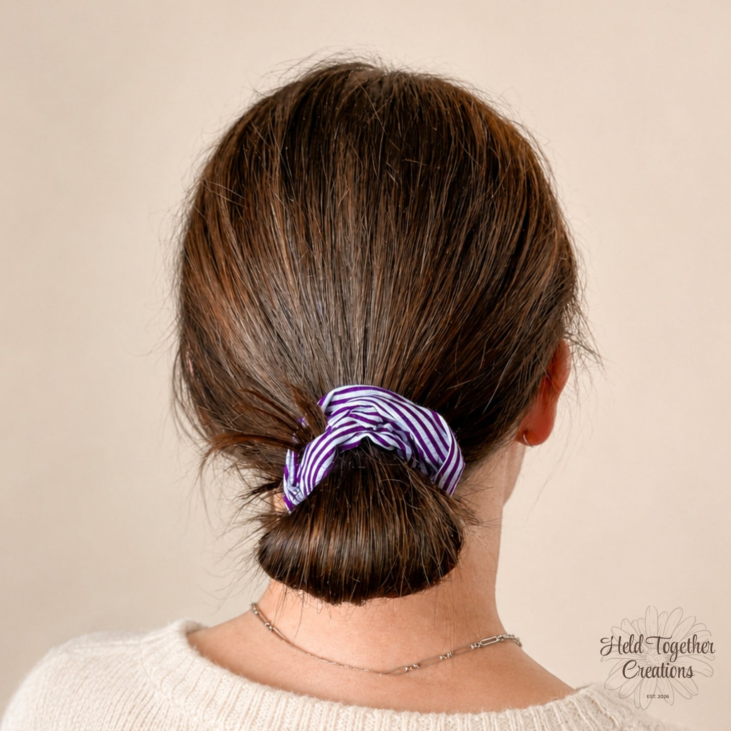 Purple and white striped scrunchie on a beige background