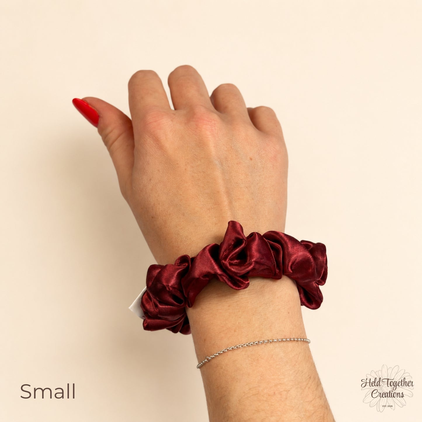Small ruby satin scrunchie on wrist showing size and colour