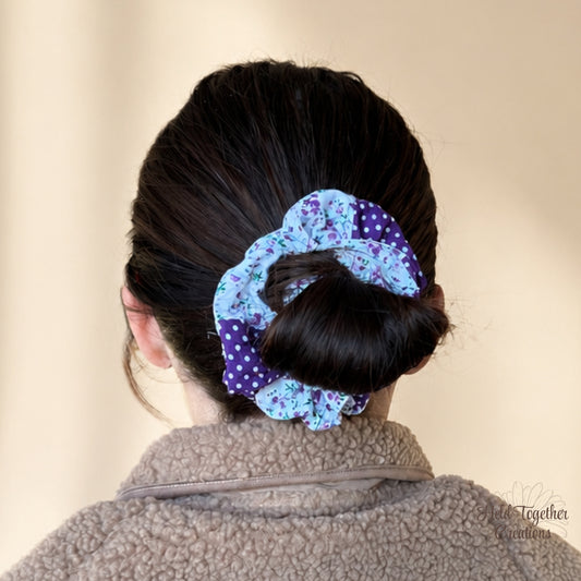 Violet Garden Scrunchie with purple polka dot and floral fabric on a warm neutral background.