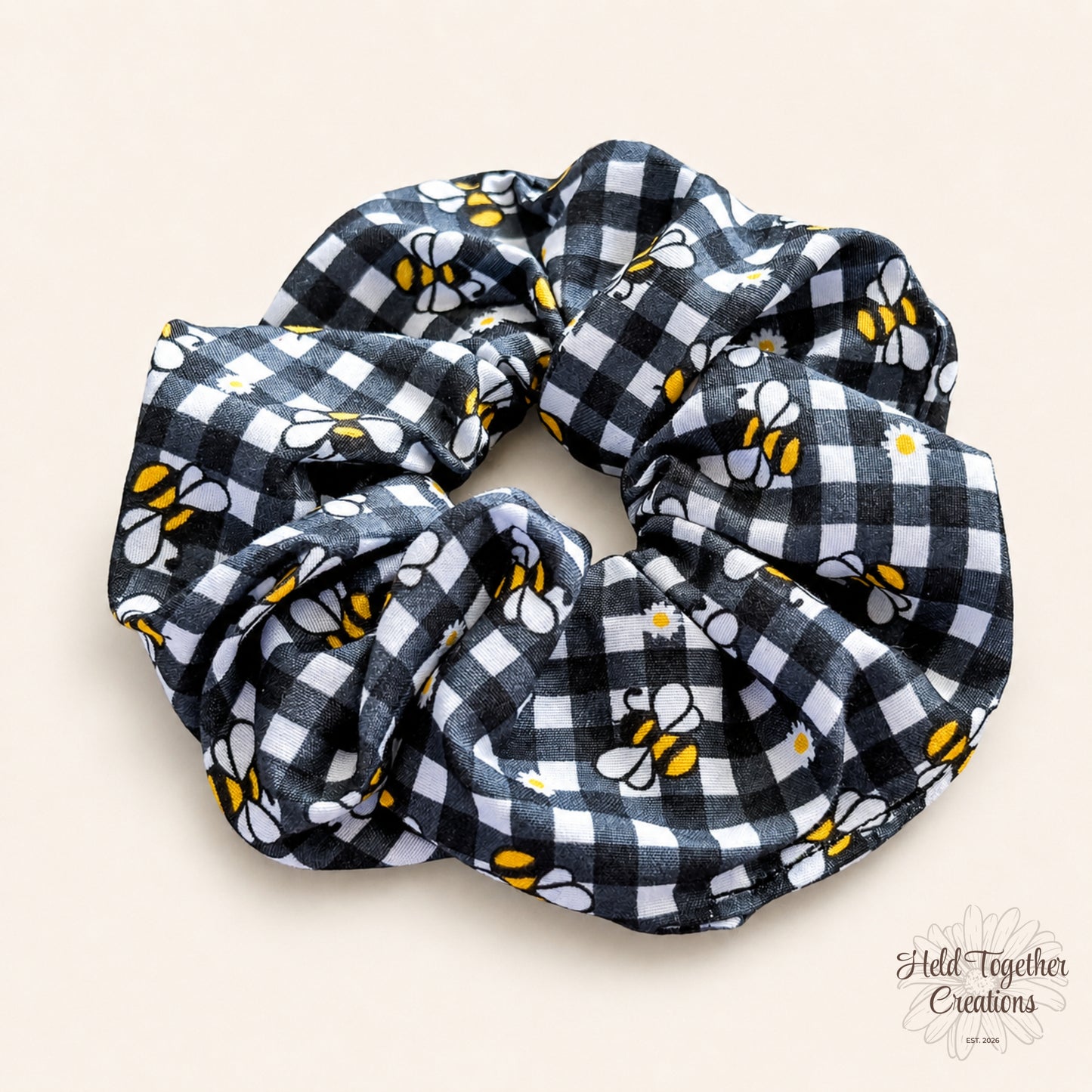 Black and white checkered scrunchie with bee pattern on a beige background