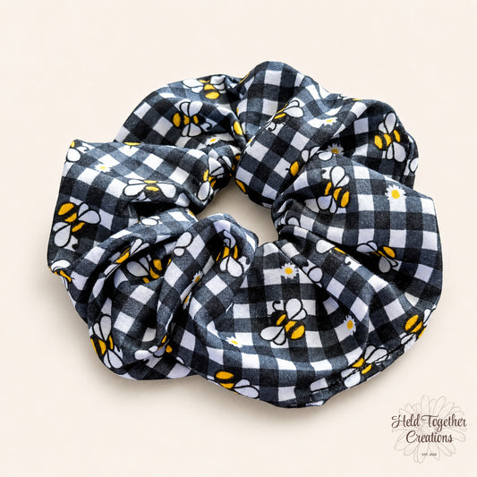 Black and white checkered scrunchie with bee pattern on a beige background