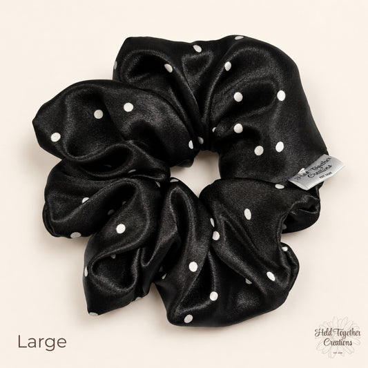 Large black satin scrunchie with white spot pattern on a soft ivory background.