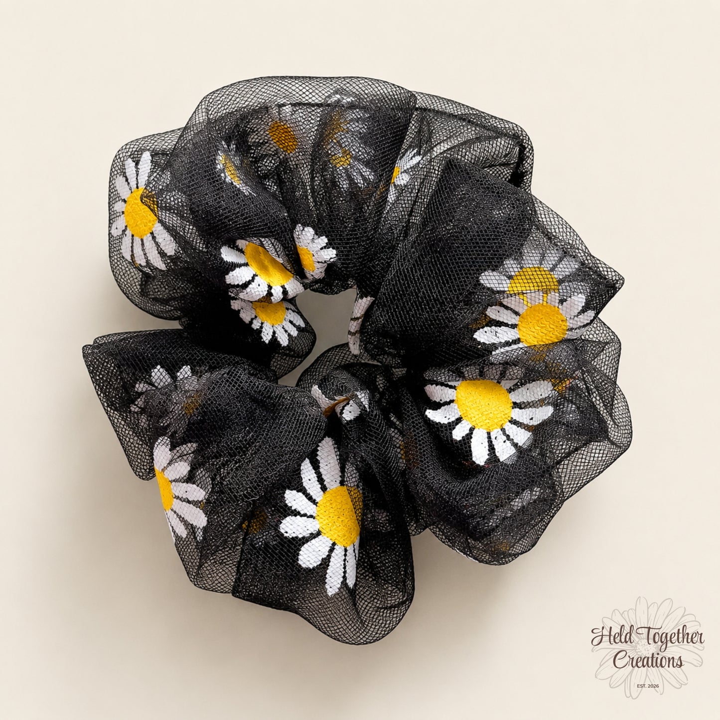 Black sheer daisy puff scrunchie on a warm neutral background