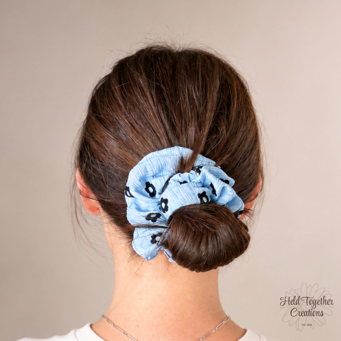 Blue Daisy Pop handmade scrunchie in textured light blue fabric with black daisy print.