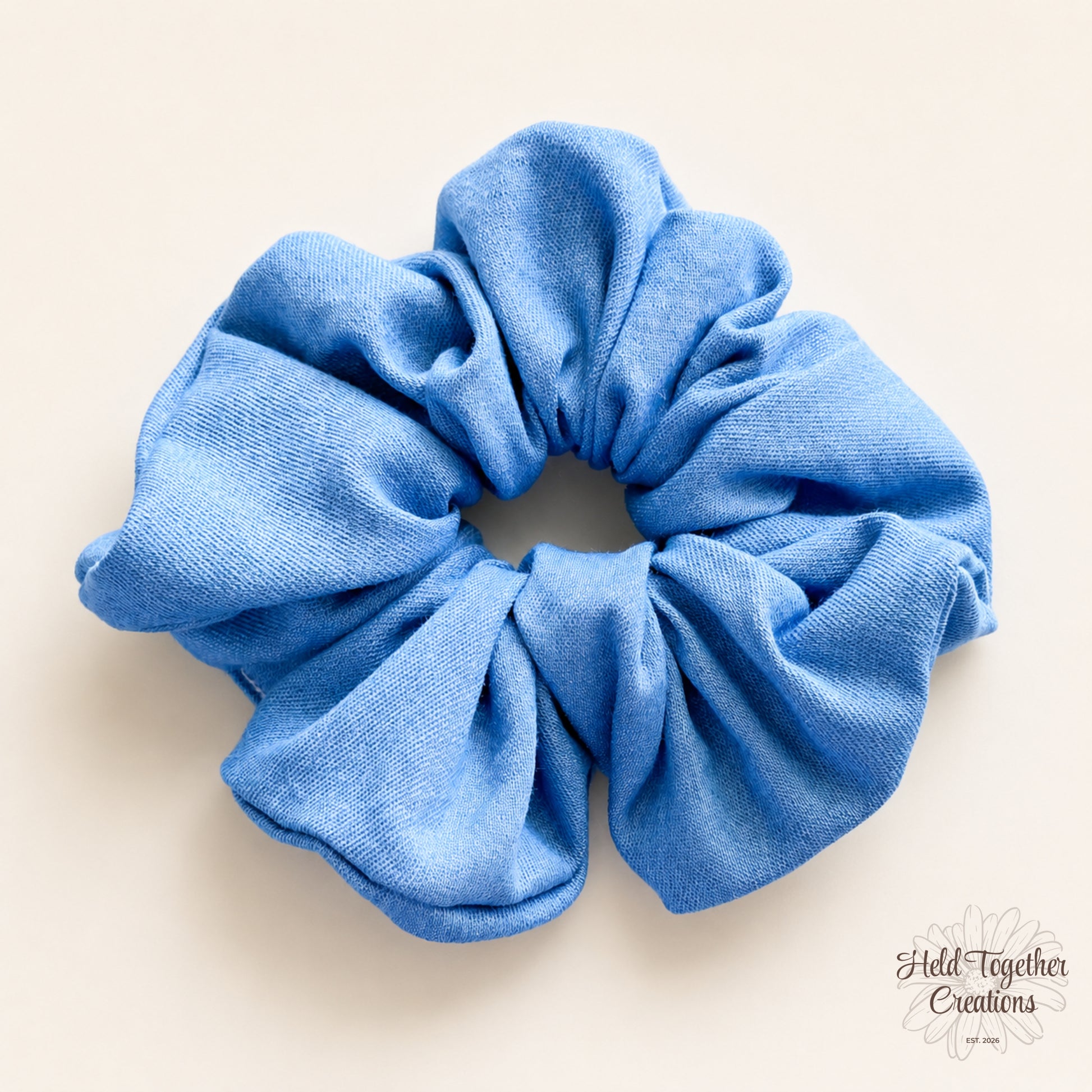 Blue Jean Baby handmade blue fabric scrunchie on a warm ivory background.