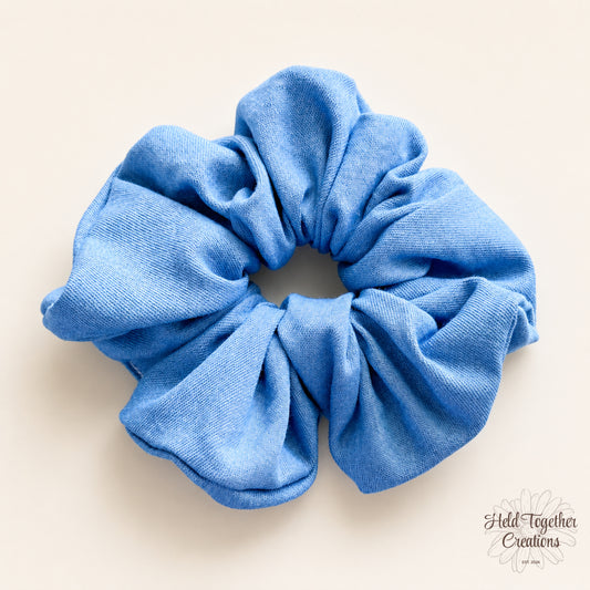 Blue Jean Baby handmade blue fabric scrunchie on a warm ivory background.