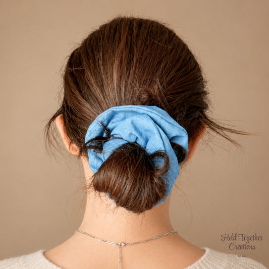 Blue Jean Baby handmade blue fabric scrunchie on a warm ivory background.