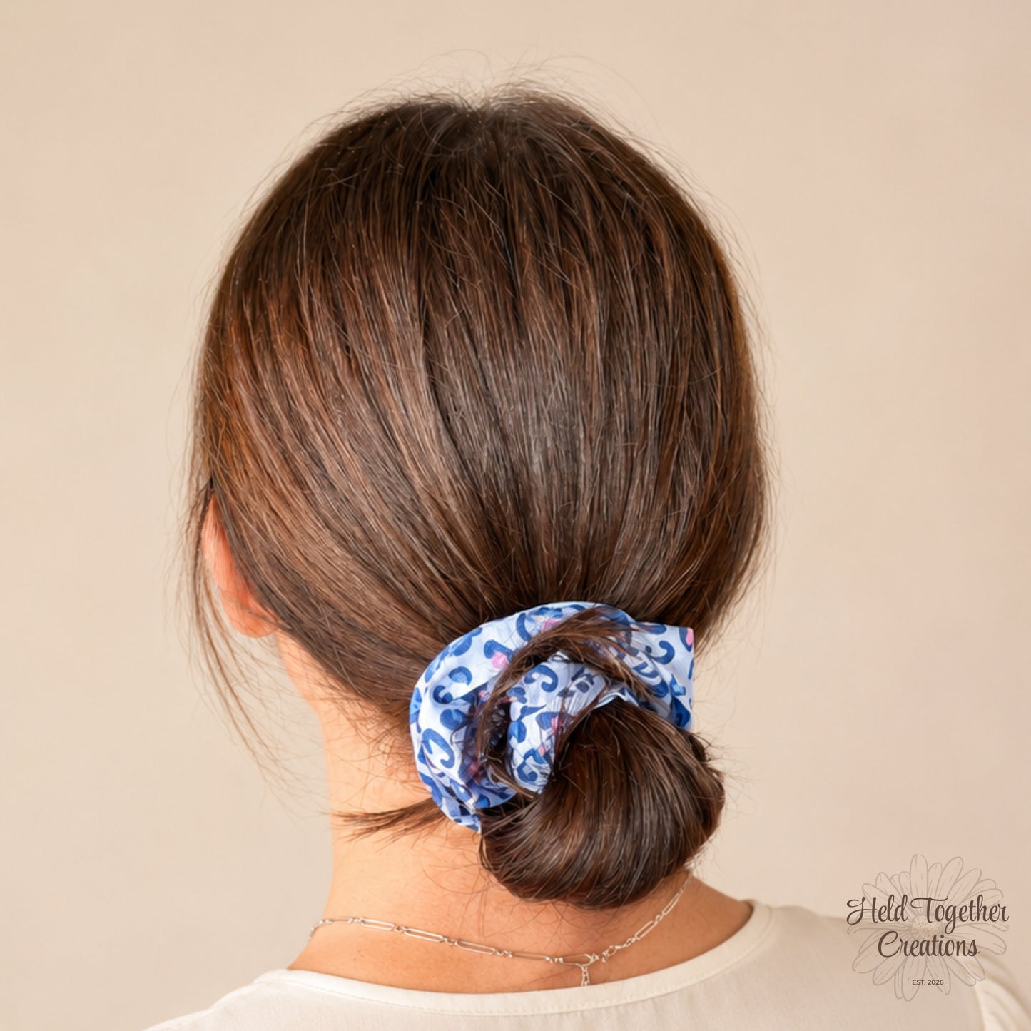 Blue Prowl handmade fabric scrunchie with a light blue base, navy leopard print pattern, and pink and yellow accent details.