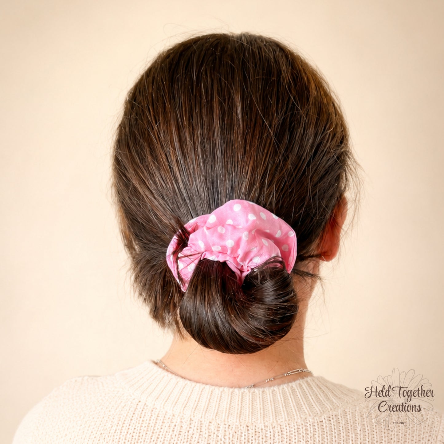 Person with a pink scrunchie in their hair on a beige background