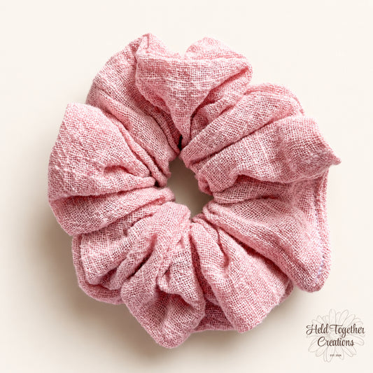 Blush pink textured linen-style handmade scrunchie on a warm ivory background.