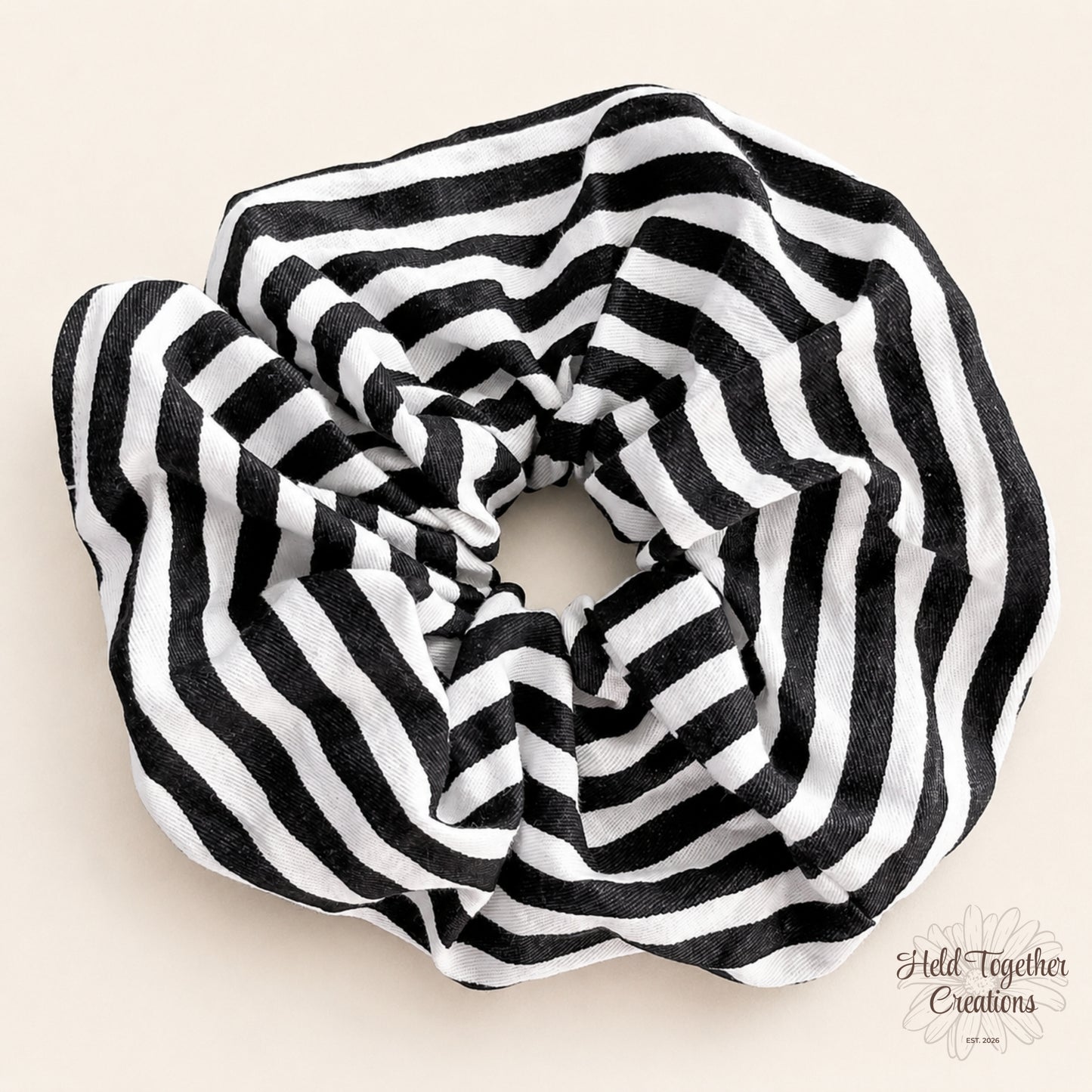Black and white Bold Stripe handmade scrunchie on a warm ivory background.
