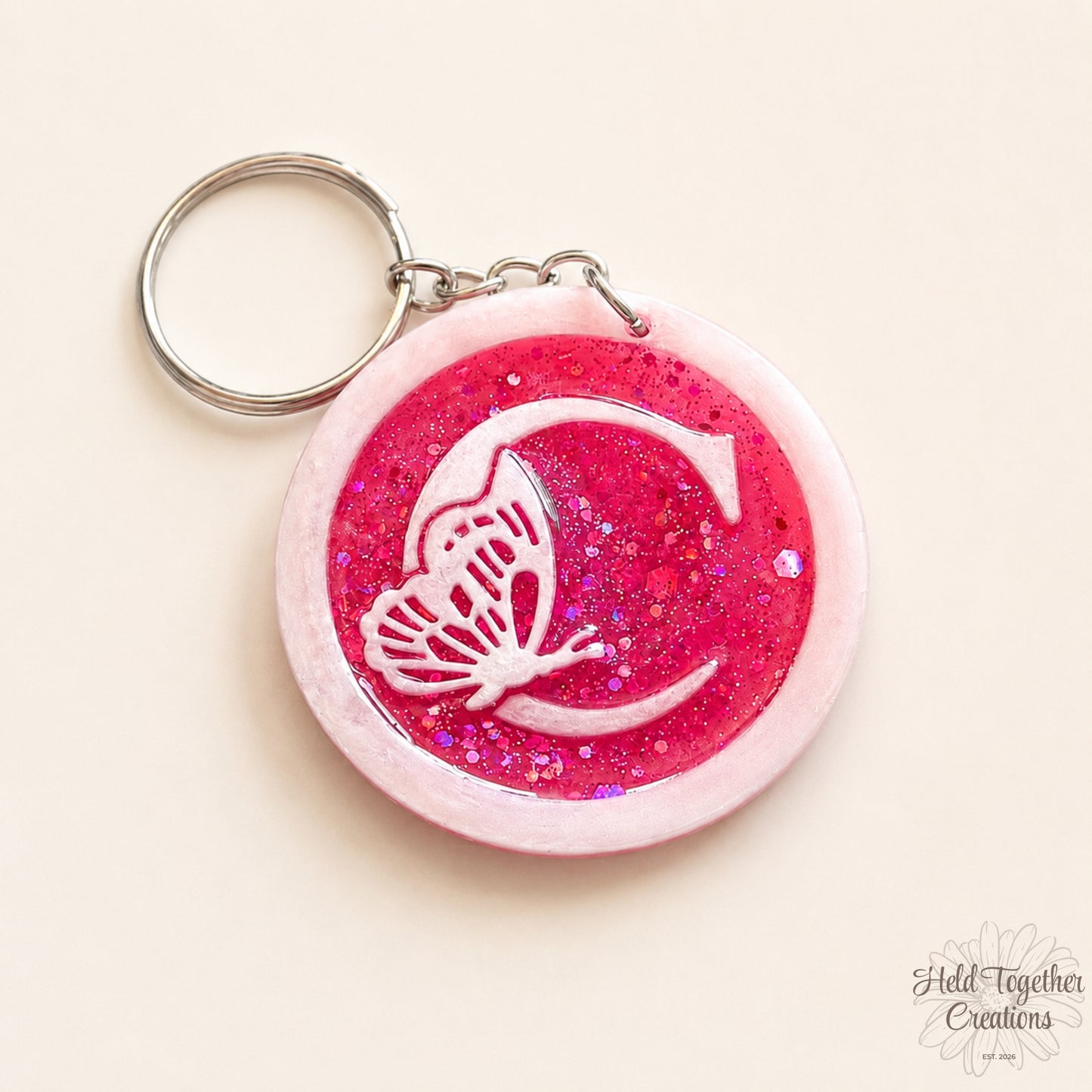 Pink glittery keychain with a butterfly design on a beige background