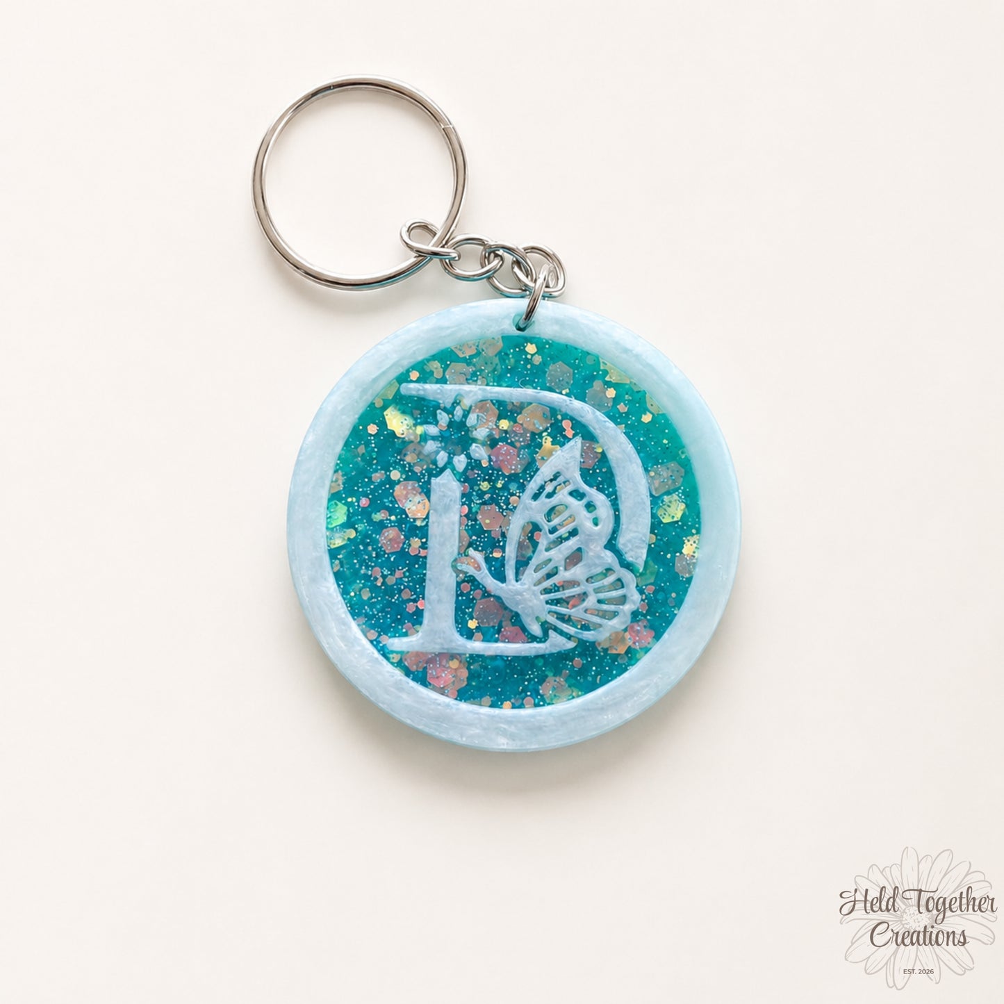 Keychain with butterfly design and glittery blue and pink finish on a white background