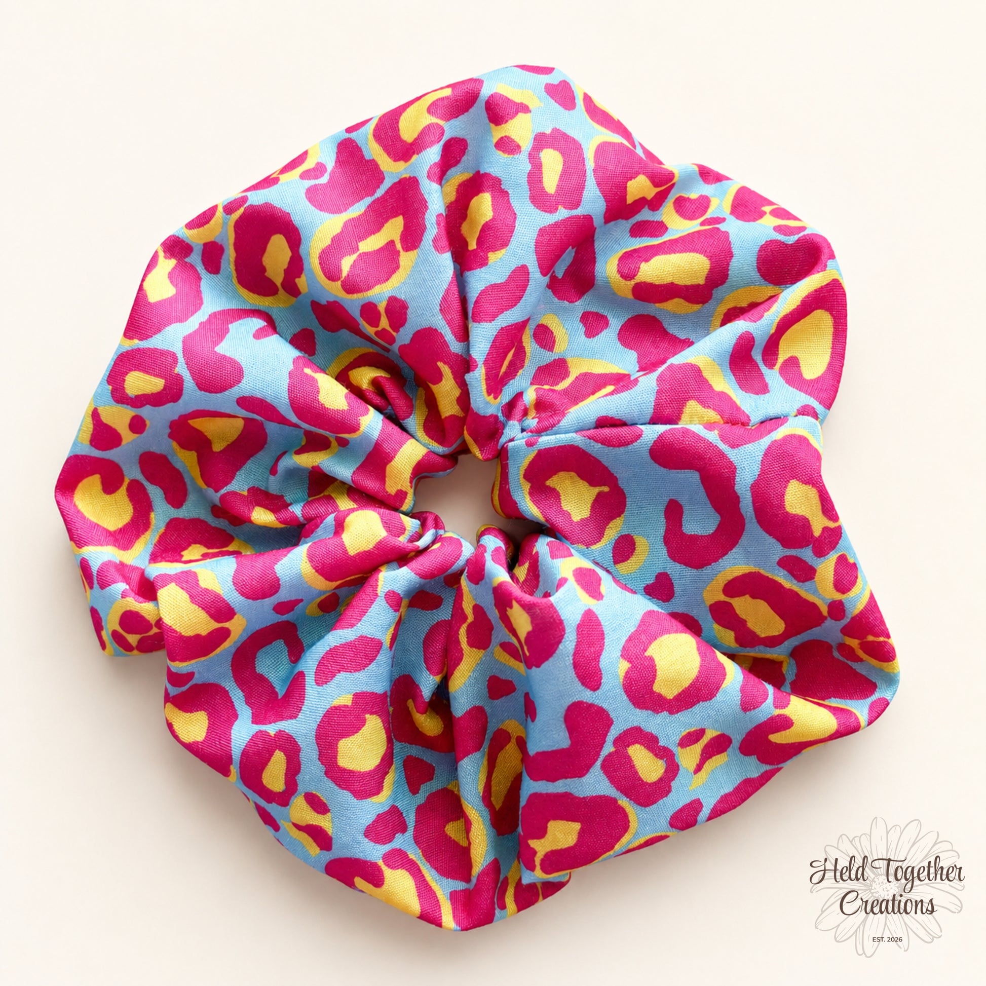 Bright blue, pink and yellow leopard print handmade fabric scrunchie by Held Together Creations.