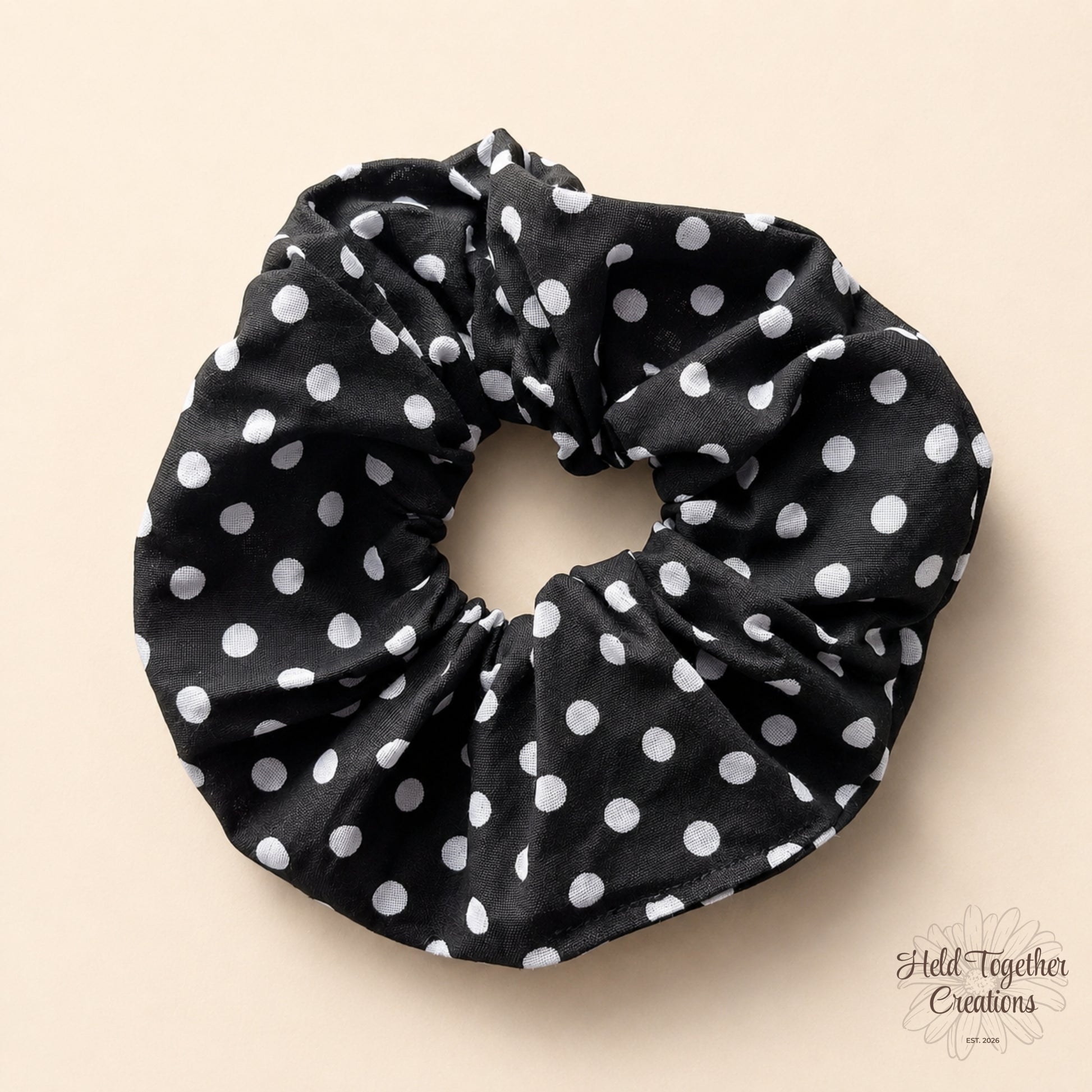 Black scrunchie with white polka dots on a beige background