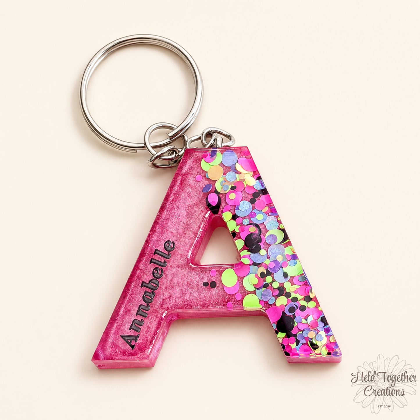 Colourful letter-shaped keychains with confetti details on a marble background