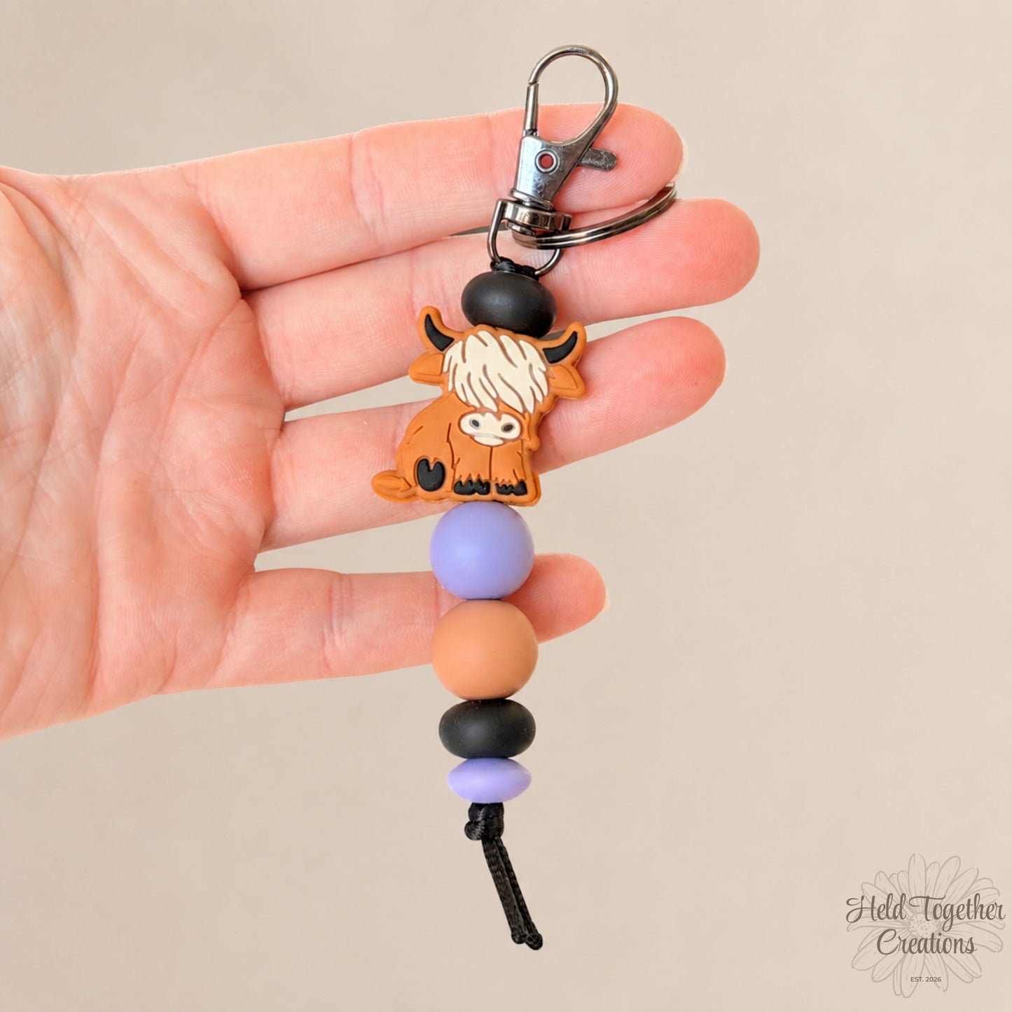 Handmade highland cow silicone bead keyrings with soft silicone beads and black keyring hardware on a neutral background.