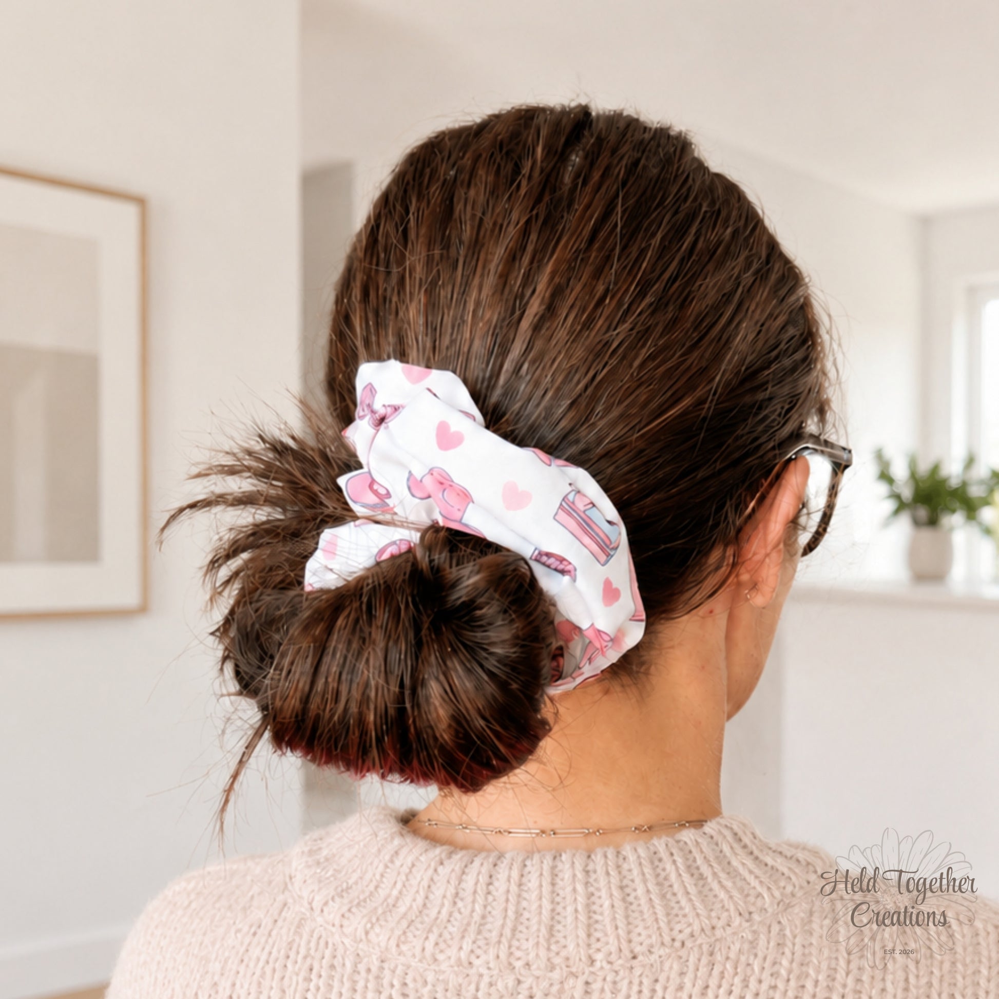 White Cowgirl Crush handmade scrunchie worn in a low bun, featuring a pink cowgirl boot and heart print on white fabric.