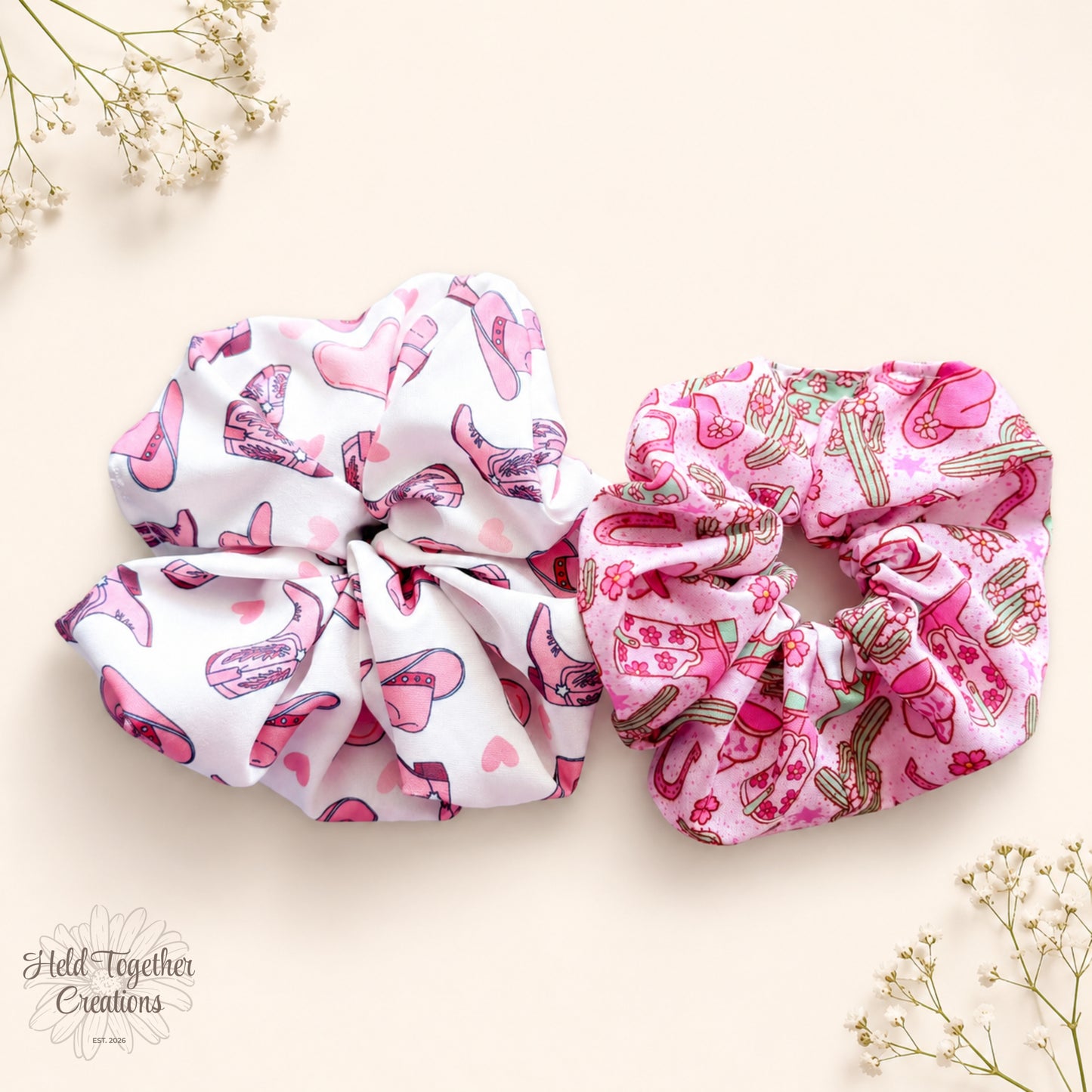 Two handmade Cowgirl Crush scrunchies on a warm ivory background, featuring pink western boot and cowgirl-inspired fabric prints.