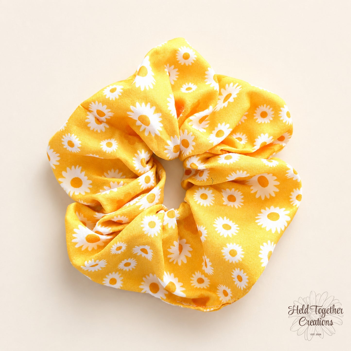 Yellow scrunchie with white floral pattern on a beige background