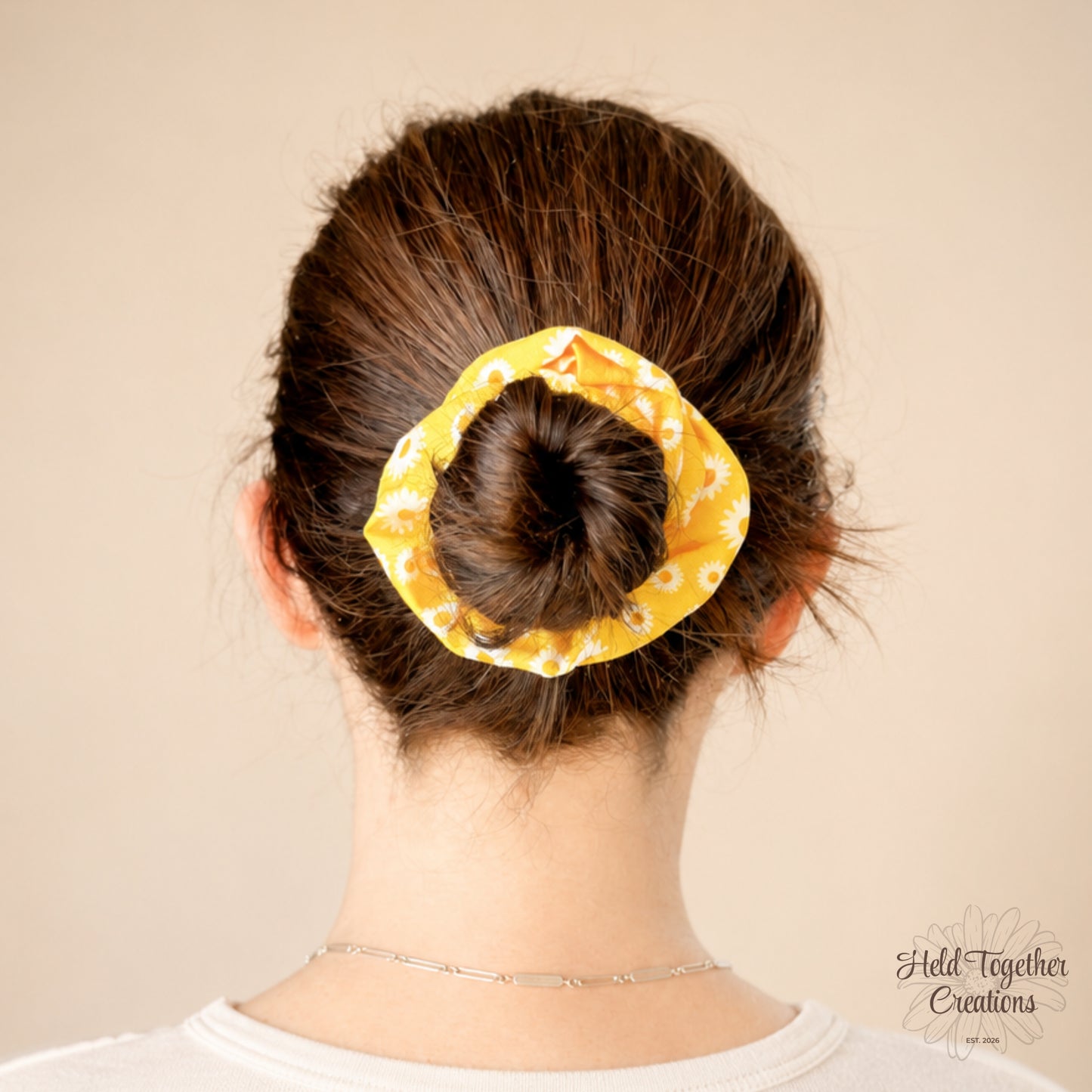 Yellow scrunchie with white floral pattern on a beige background