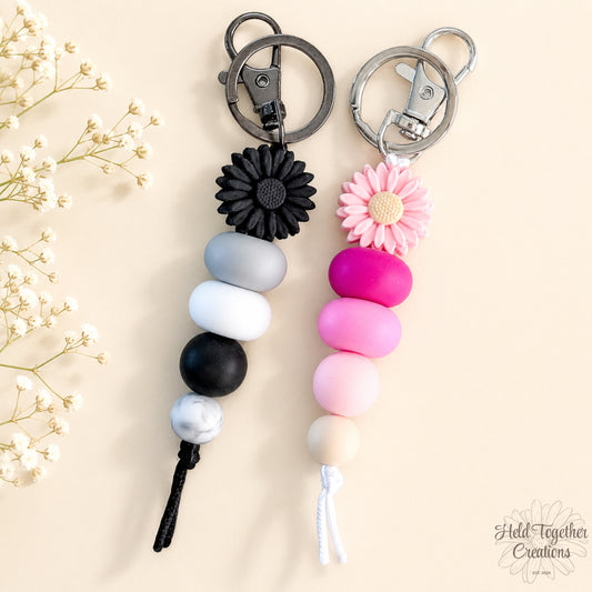 Daisy Pop handmade silicone bead keyrings in pink and black with daisy flower beads and metal keyring hardware.