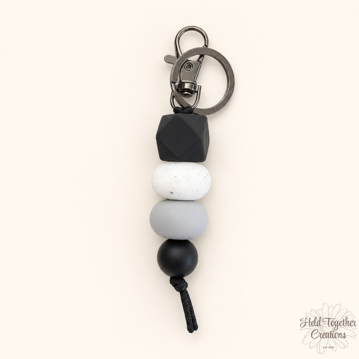 Dark & Stormy silicone bead keyring with black hex bead, white speckled bead, grey bead and black bead on a warm ivory background.