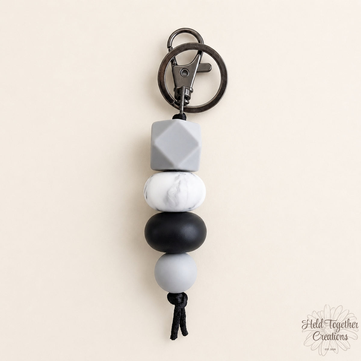 Dark & Stormy silicone bead keyring with light grey cube bead, white marble-look bead, black bead and grey bead on a warm ivory background.
