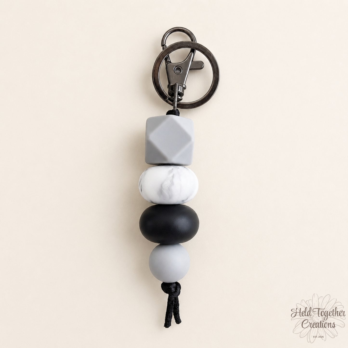 Keychain with gray, white, and black beads on a beige background