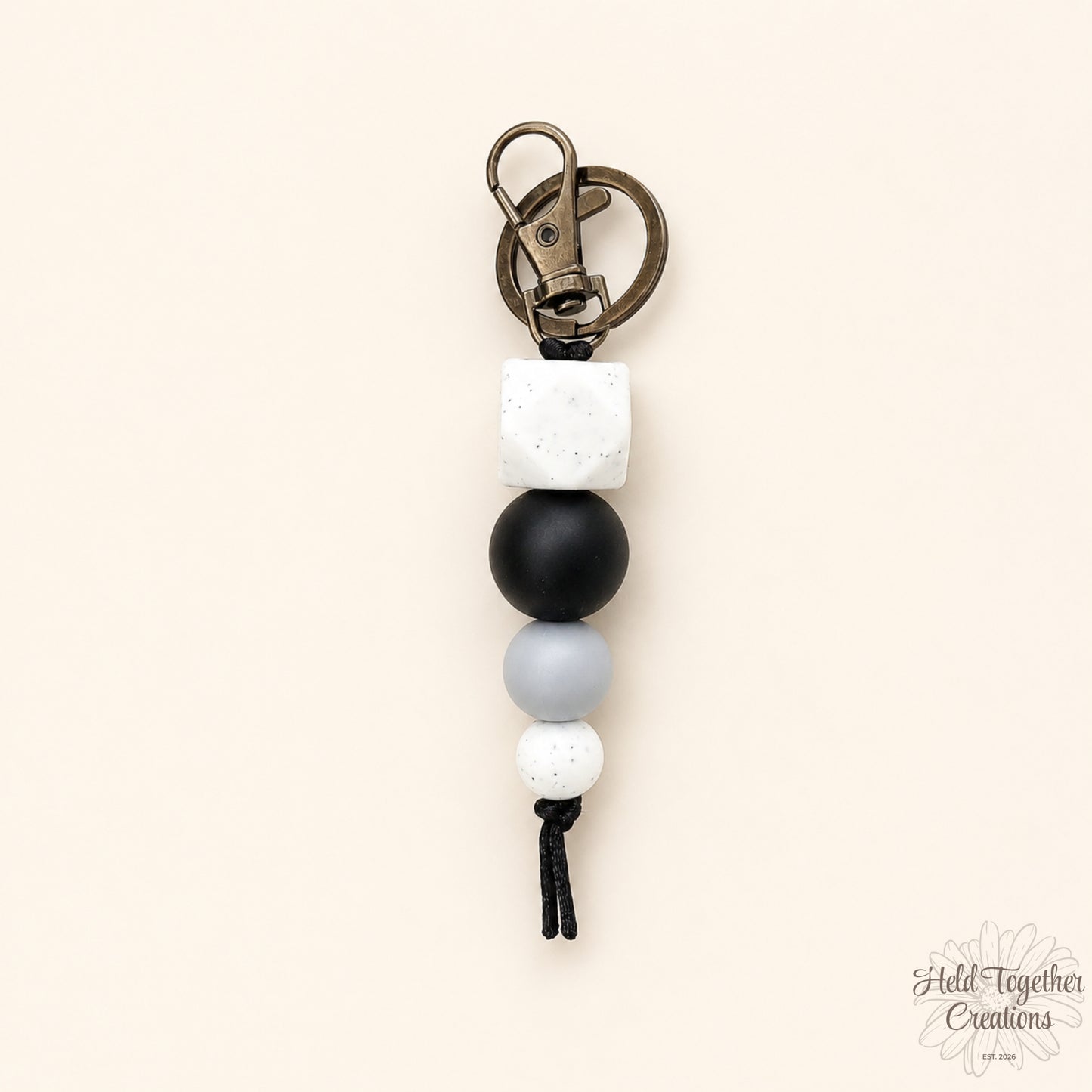 Keychain with black, white, and gray beads on a beige background