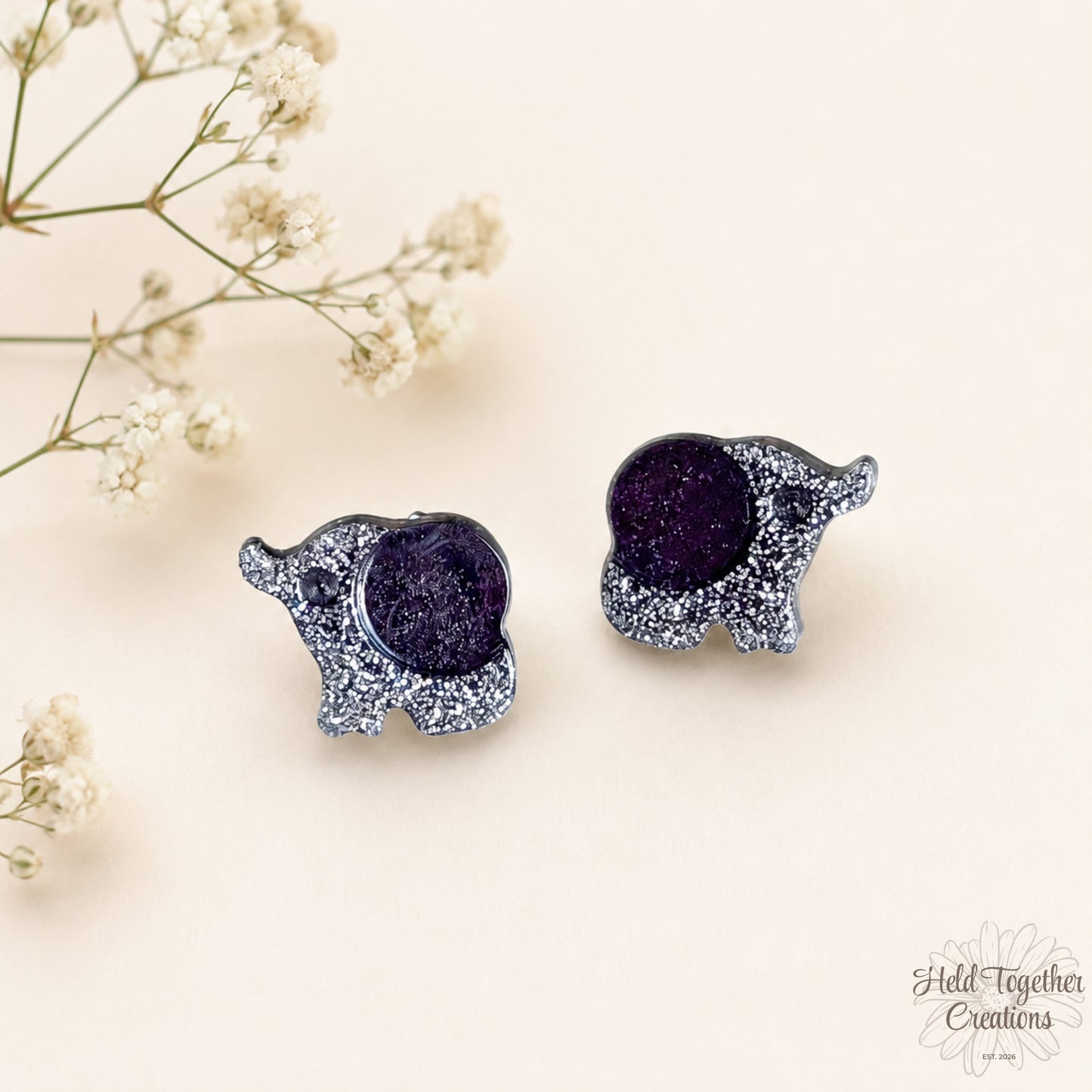 Handmade black and silver speckled elephant resin stud earrings on a soft neutral background.