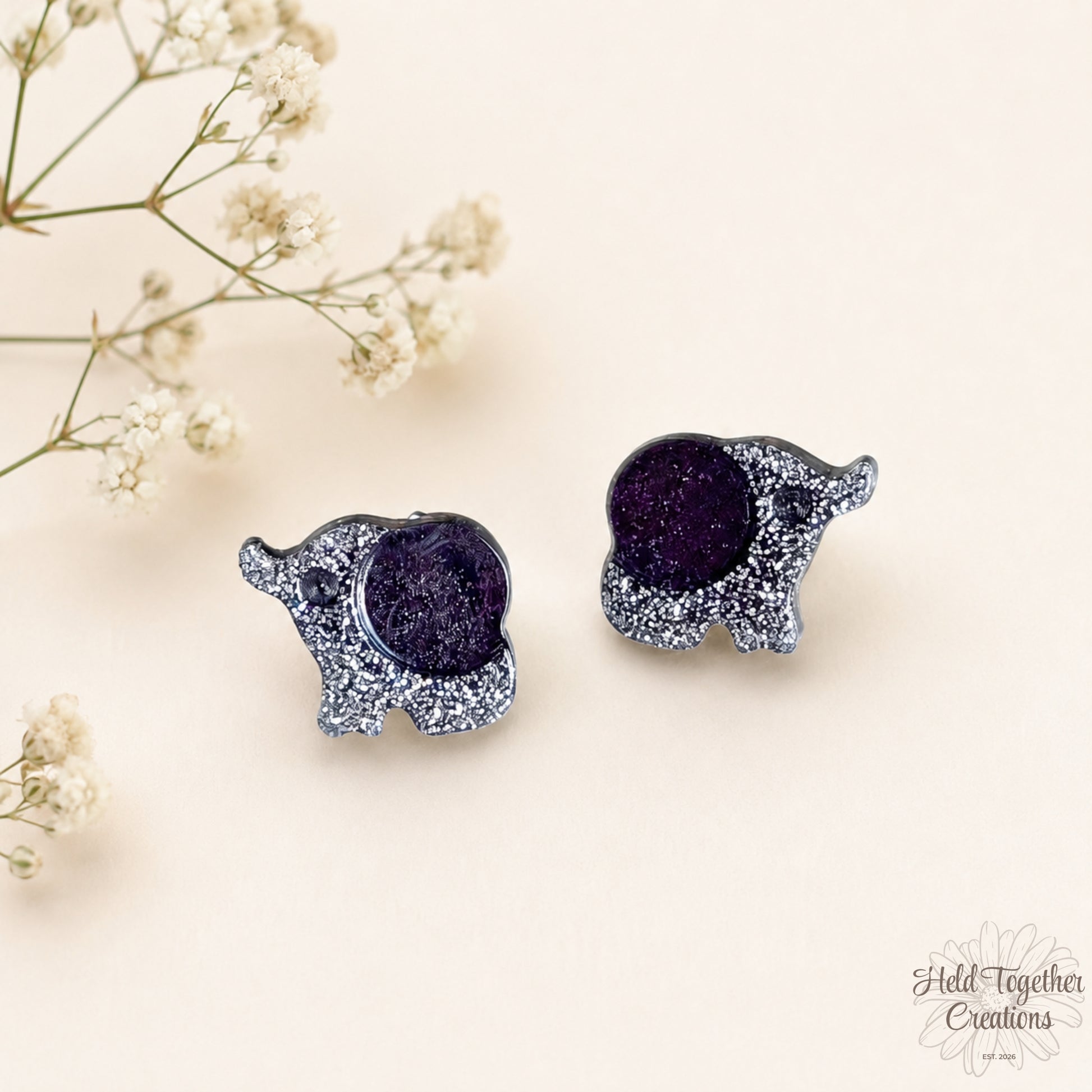 Handmade black and silver speckled elephant resin stud earrings on a soft neutral background.