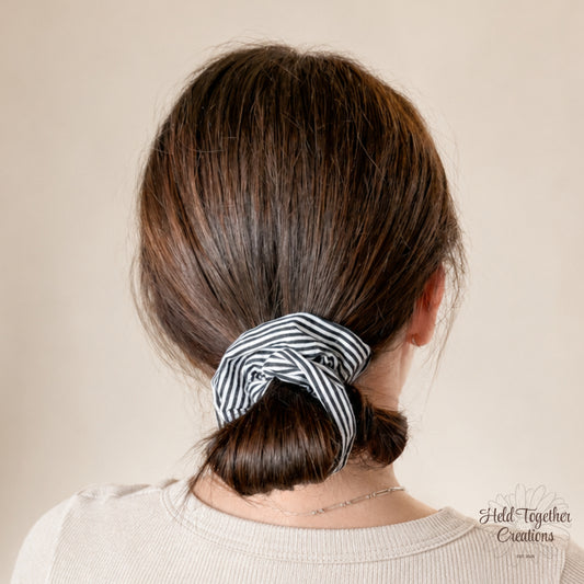 Person with a striped scrunchie in their hair against a beige background