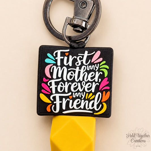 Keychain with colorful text 'First Mother, Forever My Friend' on a beige background