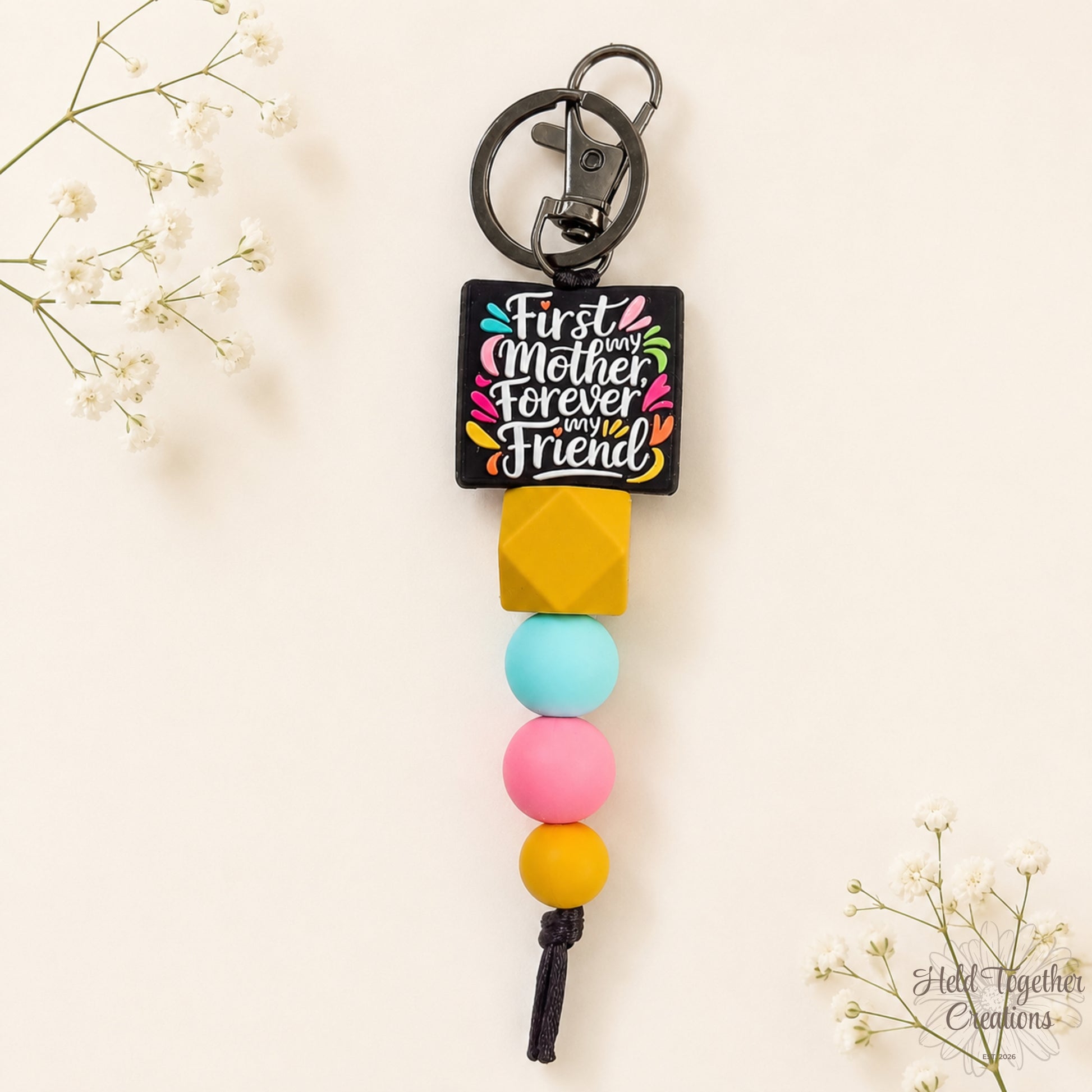 Colorful keychain with text 'First Mother Forever My Friend' on a light background
