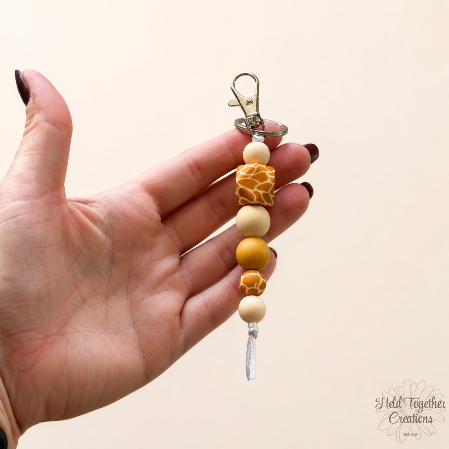 Handmade giraffe print silicone bead keyring with cream and tan beads on silver keyring hardware.