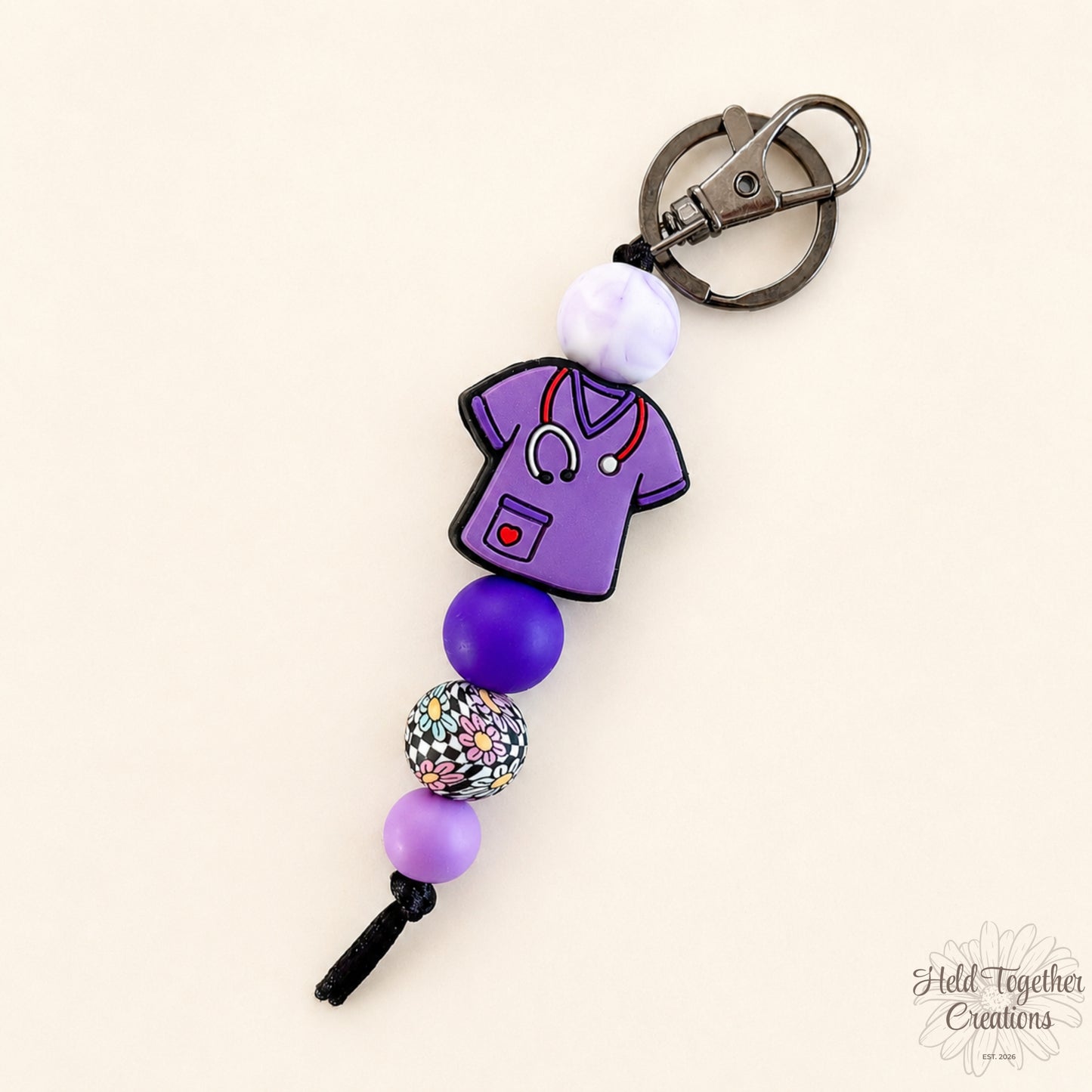 Keychain with purple scrubs design and beads on a beige background