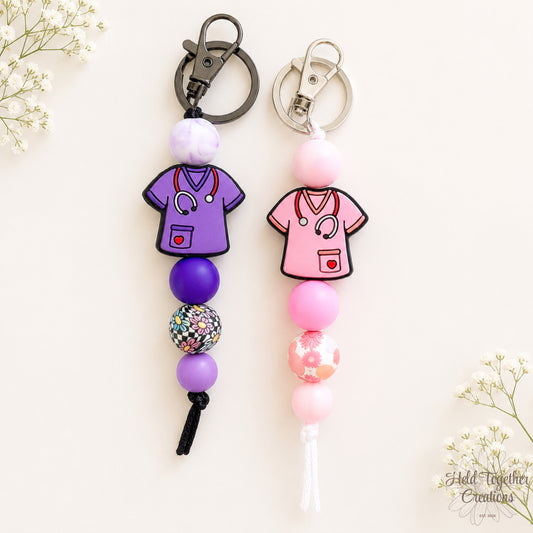 Handmade Healthcare Heroes silicone bead keyrings with purple and pink scrub charms, floral beads and metal keyring hardware.